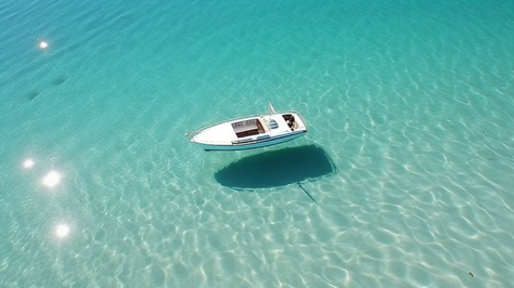 An optical illusion created by extremely clear glass-like water, white boat shadow is completely detached creating an illusion of flying...