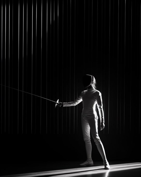 a black and white photo of a fencing player with arms in front of the sword., in the style of...